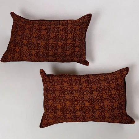 Two rust-patterned cotton throw pillows on white backdrop
